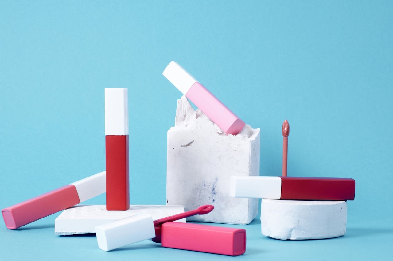 services-02 Colorful lip glosses arranged artistically against a blue backdrop showcasing vibrant hues.